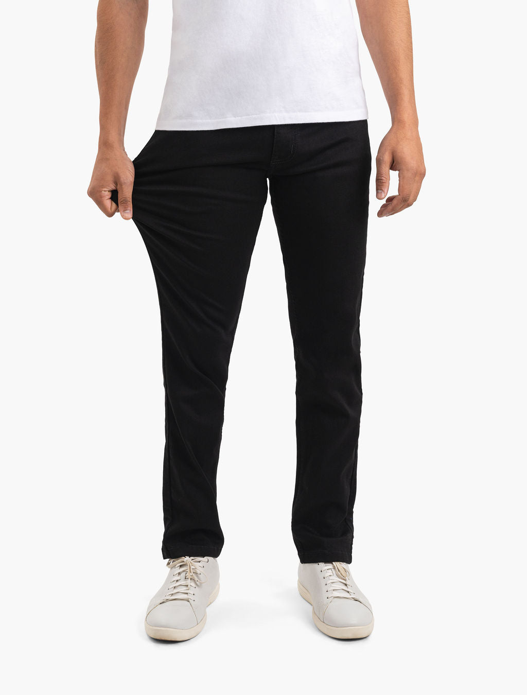 Men's black slim stretch pants shown waist-to-shoes; model pulls thigh to demonstrate fabric stretch.
