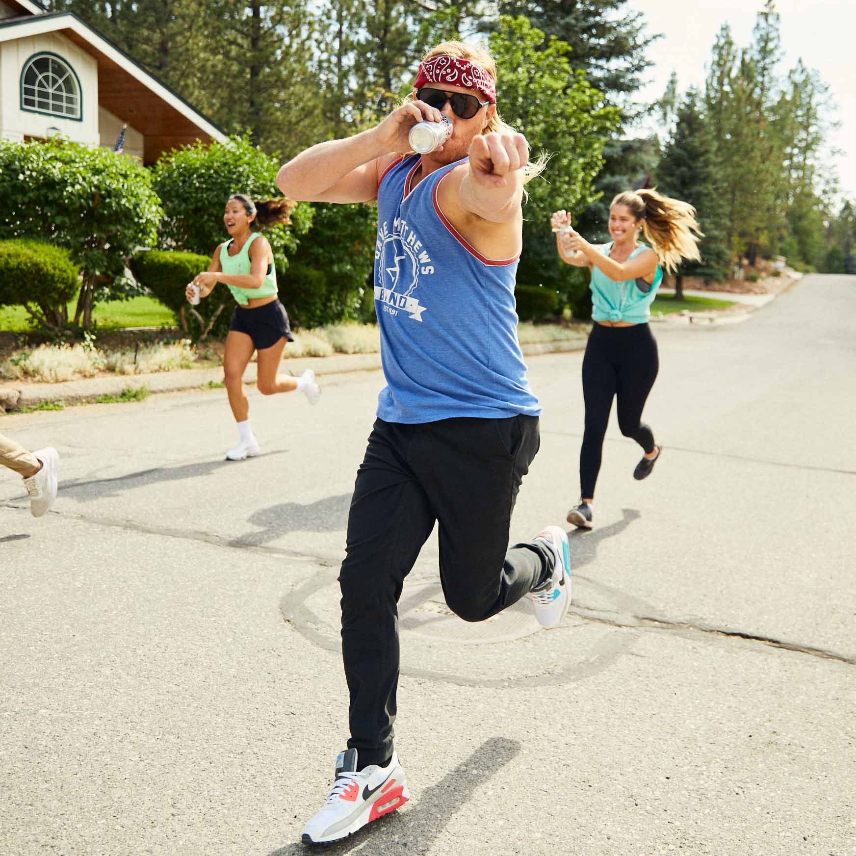 A man running in athletic wear with a group of people in a neighborhood.
