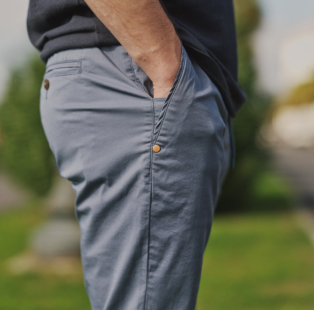 Side view of a person wearing gray pants with a button detail.