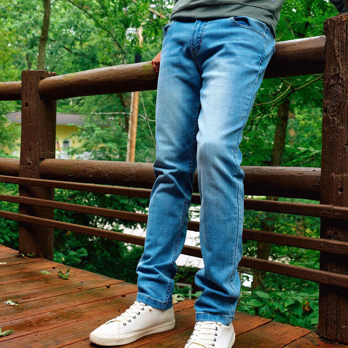 Model wearing vintage-washed jeans on a wooden deck.