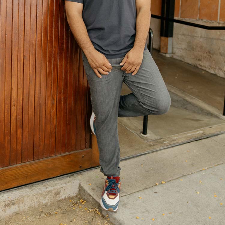 A person wearing gray pants and colorful sneakers, standing outside.
