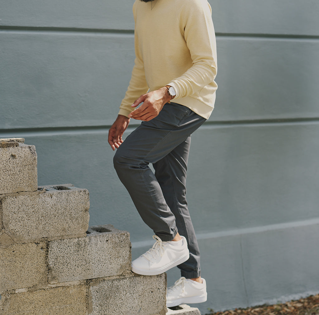 Person wearing a yellow sweater and gray pants climbing stairs