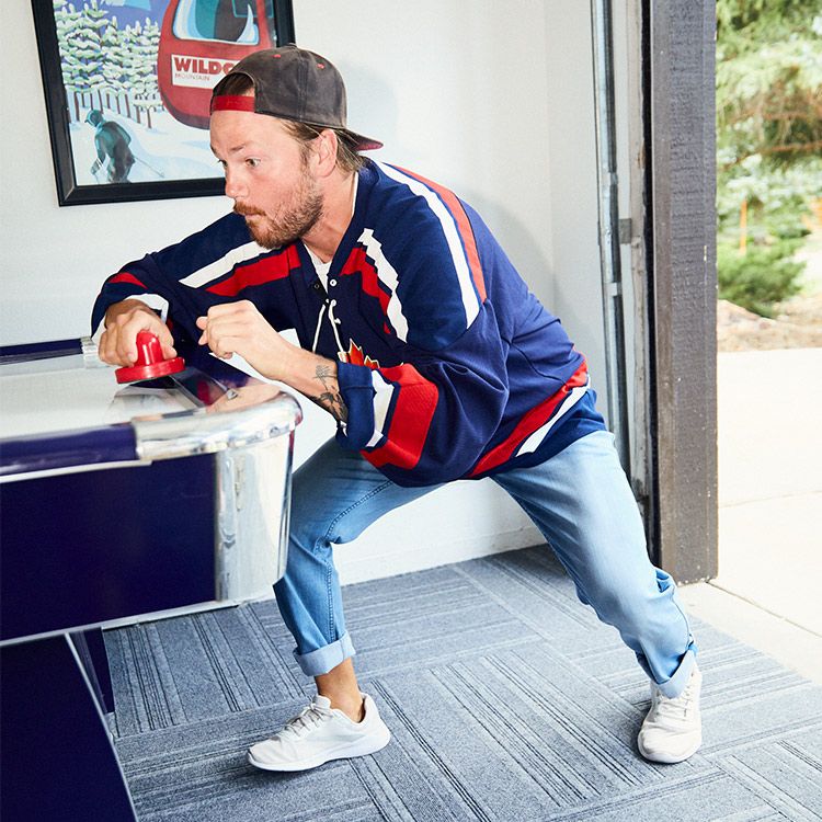 A man in a colorful jersey playing air hockey in a casual setting.