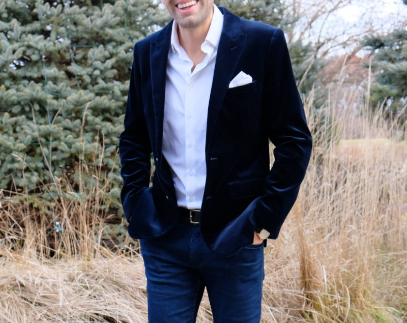 Man in a navy velvet blazer with a white shirt and pocket square, standing outdoors