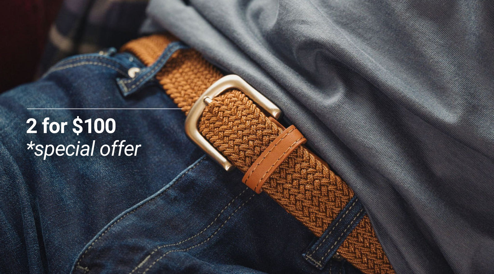 Close up of woven tan belt with silver buckle showcasing braided texture against blue jeans and gray shirt background