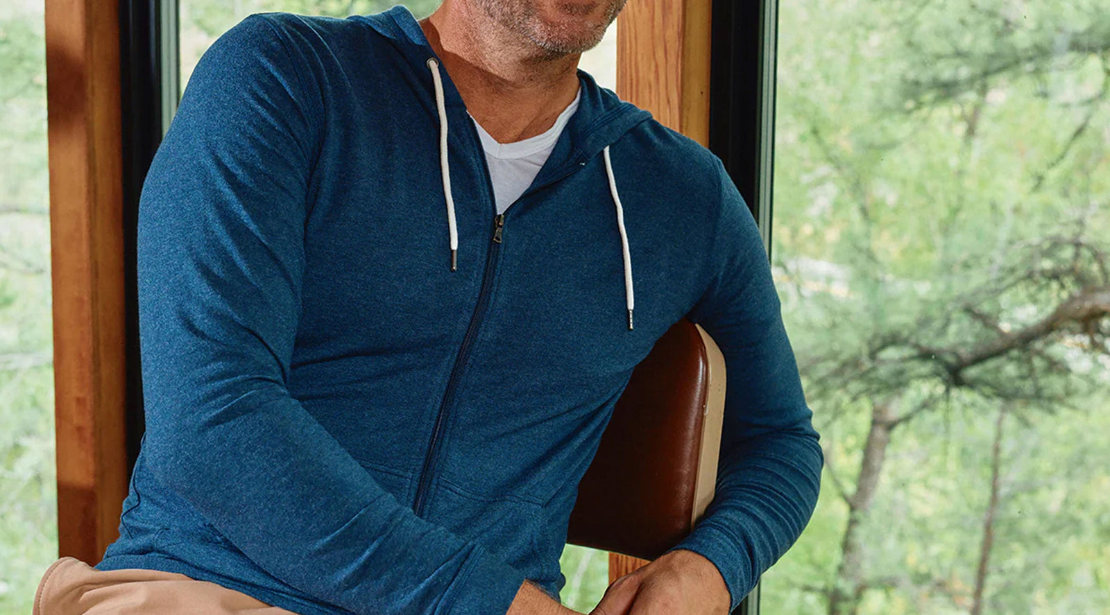 Three-quarter view of Cashtech zip-up hoodie in heather blue showing full zip, hood, white drawstrings and pockets
