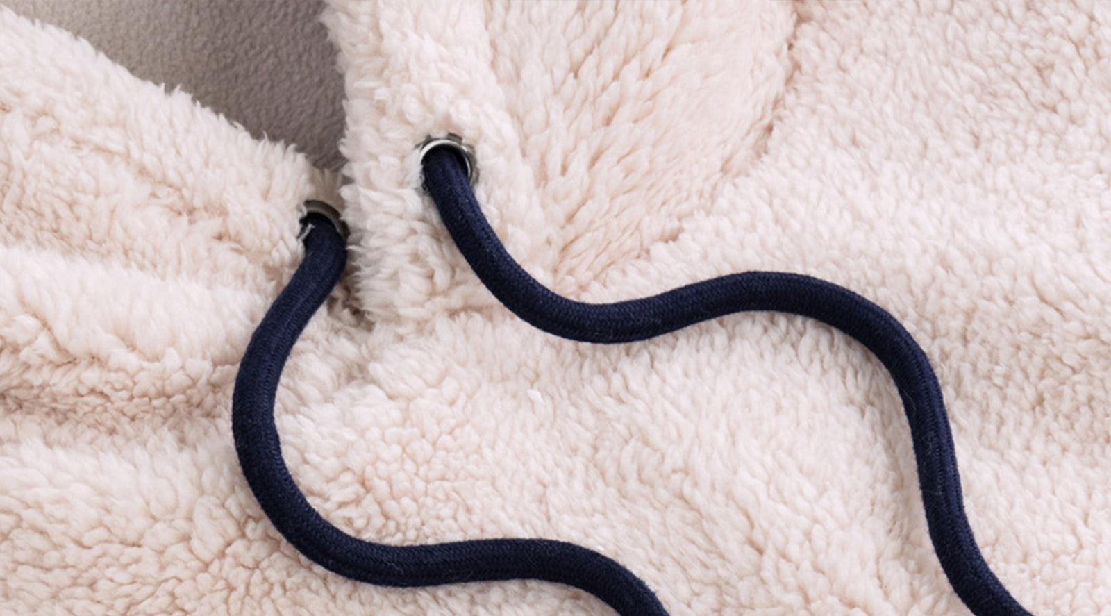 Close-up of sherpa fleece hoodie showcasing plush cream texture and navy drawstring through metal grommets