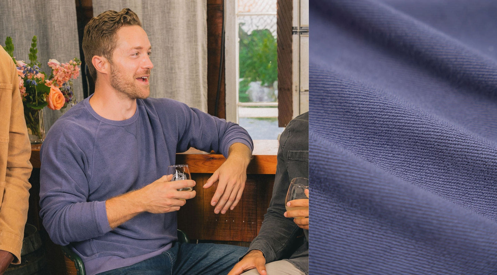 Three-quarter view of a blue terry-knit crewneck on a seated man showcasing textured terry fabric and relaxed fit with wooden bar interior background