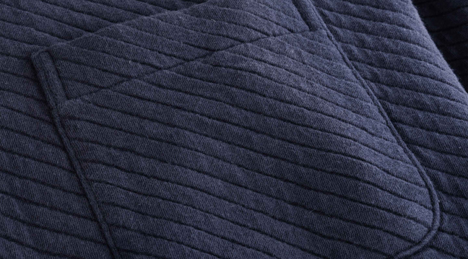 Close-up of navy diamond knit top showing diagonal quilted stitch texture and pocket seam