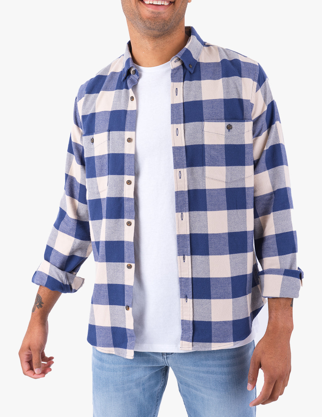 Model wearing blue-and-beige buffalo-plaid button-up shirt over white T-shirt, sleeves rolled, paired with light-wash jeans.