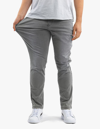 Front view of gray pants showcasing stretch fabric pulled at the thigh and tapered fit on a light background