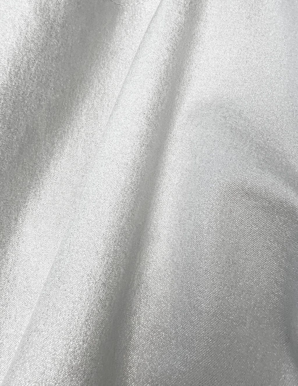 Draped champagne-colored satin fabric showing soft sheen and diagonal folds.