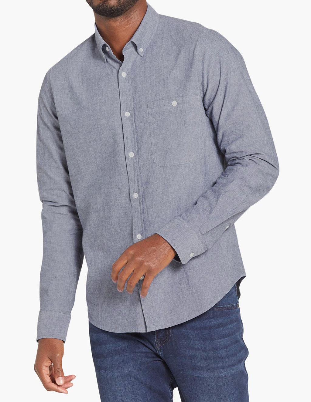 Model wearing a blue chambray button-down shirt with long sleeves and a collar.