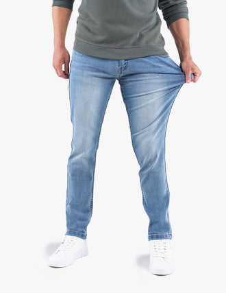 Front view of light wash slim-fit jeans on model stretching the thigh to show stretch fabric on white background
