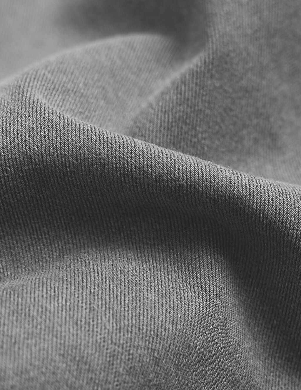 Close-up of gray woven fabric showing diagonal twill weave and soft folds