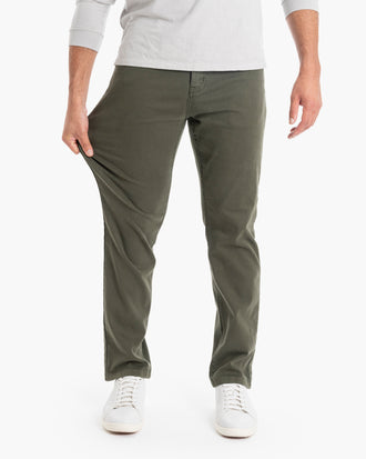 Men's olive-green stretch casual pants, waist-to-shoes view; model pulls fabric at thigh to show stretch.