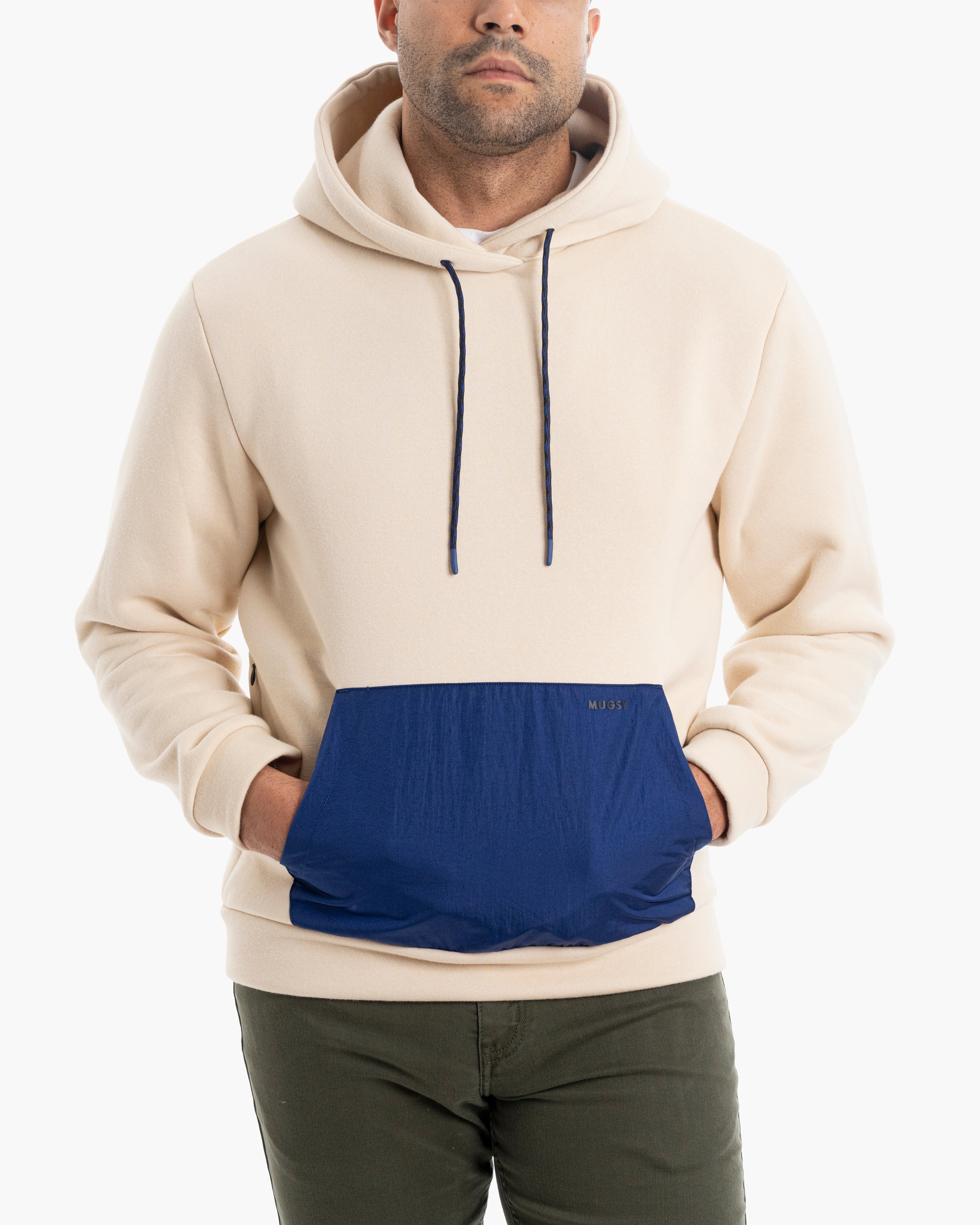 A man wearing a cream and navy hoodie with a front pocket.