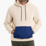 A man wearing a cream and navy hoodie with a front pocket.