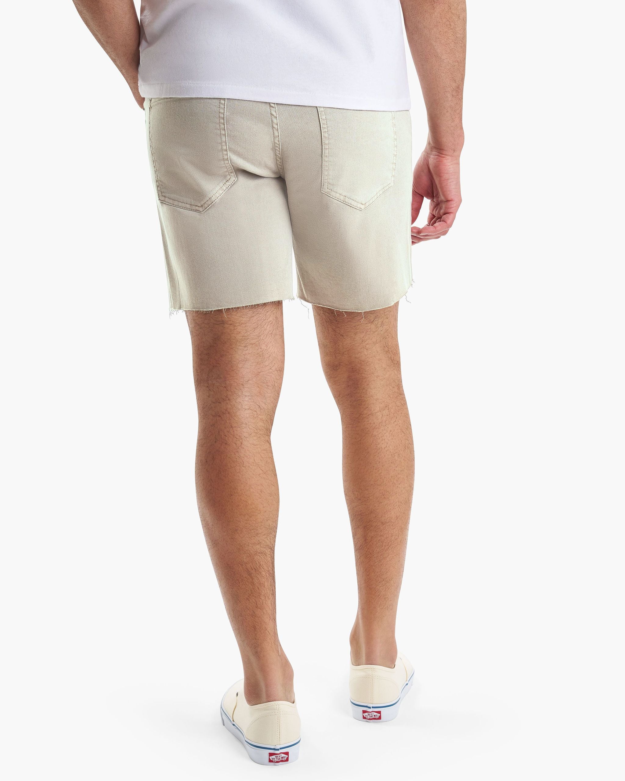 Man wearing beige shorts and white slip-on shoes, viewed from the back