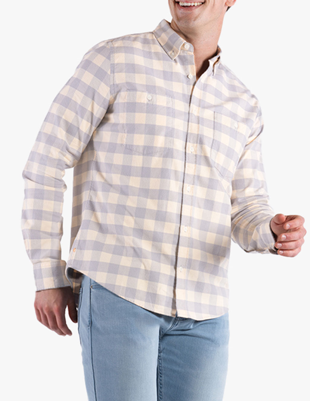Man wearing a light-colored checkered button-up shirt and light blue jeans, smiling and posing.