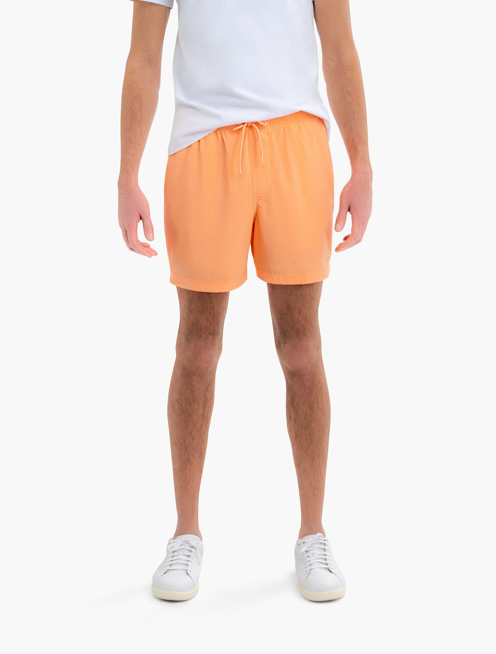 Front view of Daybreaks men's swim trunks in peach orange with elastic drawstring waist and mid thigh fit on white background