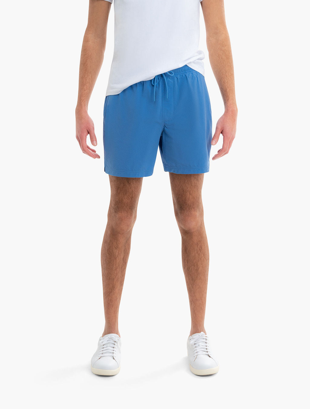 Front view of men's Pacifics swim trunks in blue on model, showing mid-thigh length and drawstring waist on white background