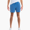 Front view of men's Pacifics swim trunks in blue on model, showing mid-thigh length and drawstring waist on white background