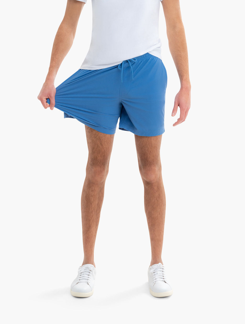 Front view of Pacifics swim shorts in blue on model showing 6-inch inseam and textured 4-way stretch fabric on white background