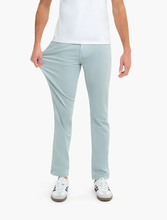 Front view of Classic fit mint garment-dyed jeans on model showcasing stretch fabric as model pulls fabric at thigh, white background
