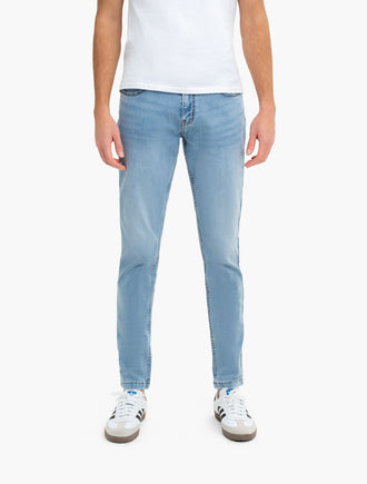Front of Daytonas Tapered jeans on model showing light vintage wash and slim tapered ankle fit on white background