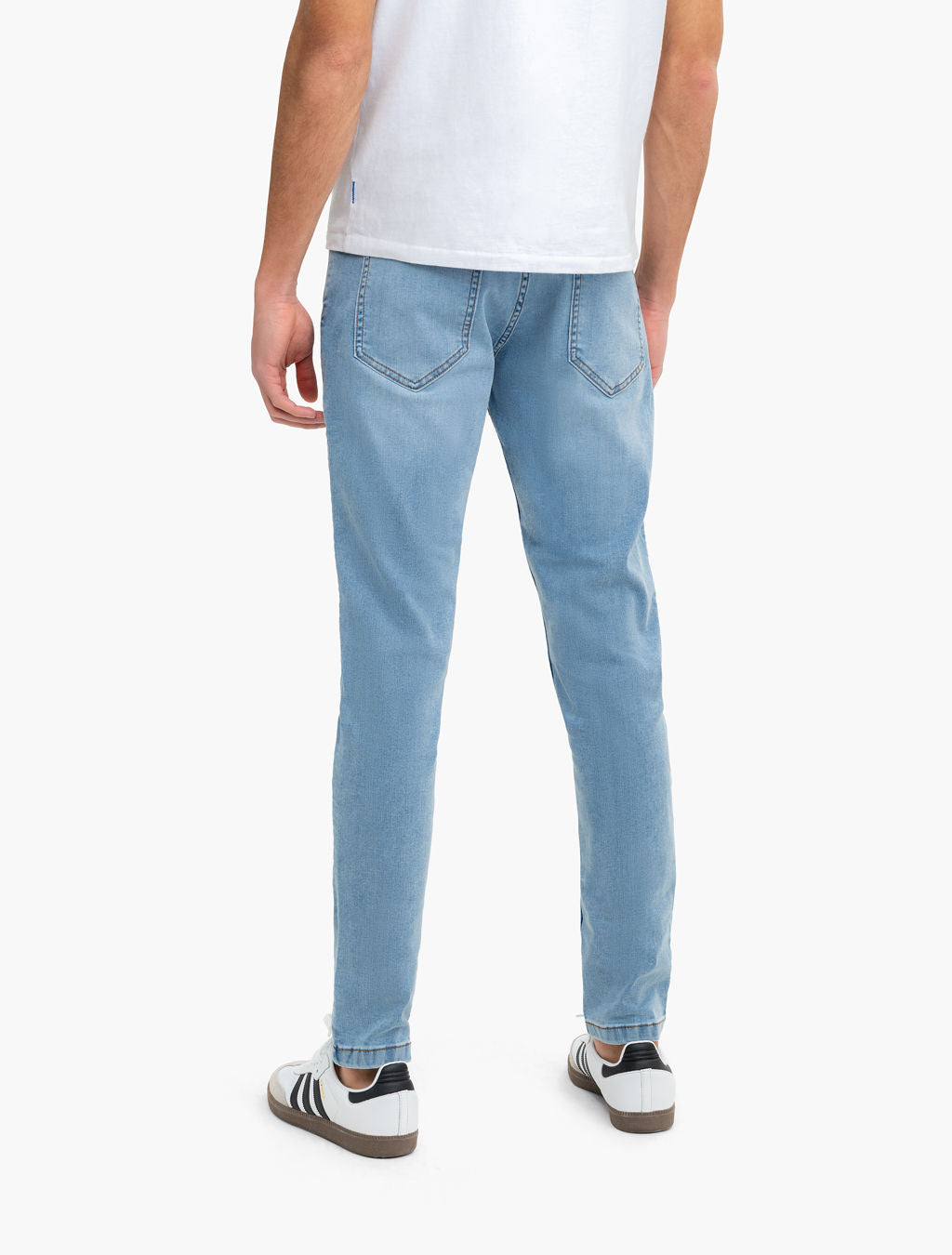 Rear view of Daytonas Tapered jeans in vintage washed light blue showing tapered slim fit and back pockets on model against white background