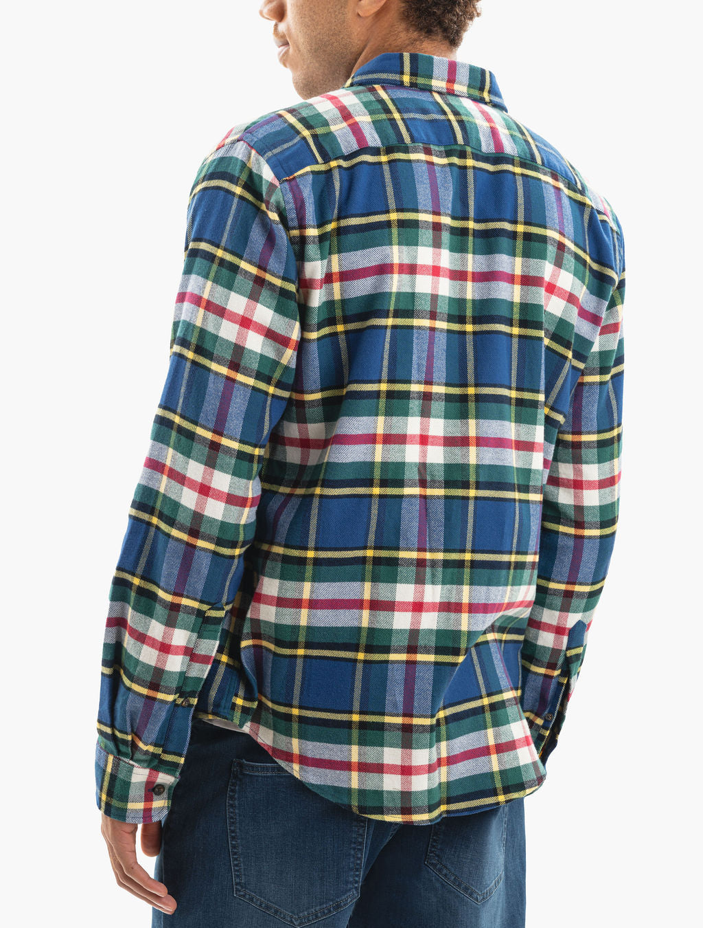 Back view of a person wearing a blue, green, red and yellow plaid flannel shirt, untucked over jeans.