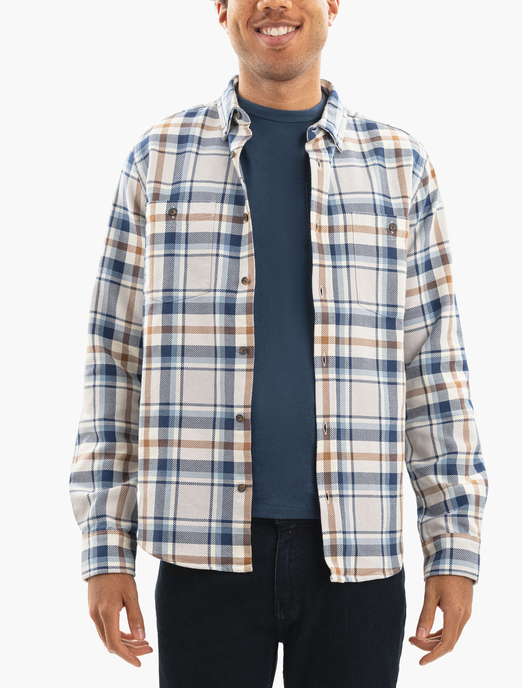 Smiling man shown from chin to hips wearing a navy T-shirt and beige-and-blue plaid button-up shirt, hands at sides.