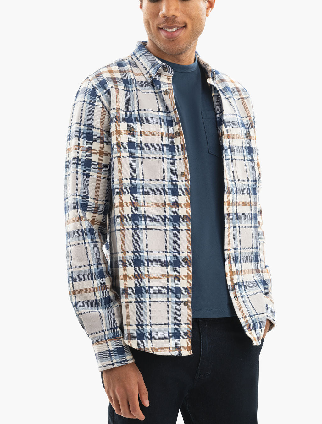 Man wearing blue-and-tan plaid button-down shirt over navy T-shirt, right hand in pocket, cropped at hips.