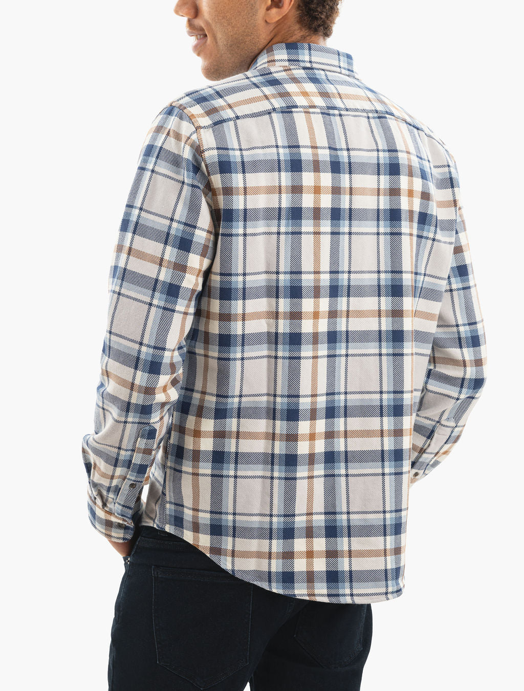 Back view of man wearing blue, tan and white plaid flannel shirt and dark jeans, hands in pockets