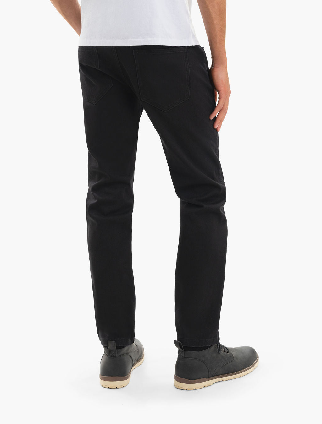 Back view of a model wearing slim black jeans and gray lace-up boots, white tee hem visible