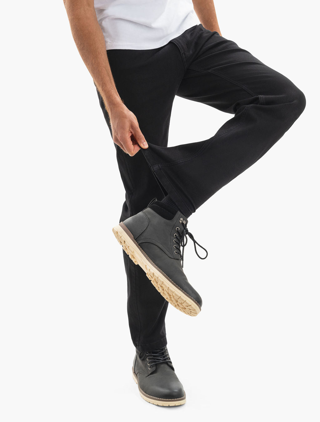 Person's lower legs in black pants with ankle zipper pulled open, black lace-up boots with beige soles.