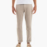 Men's beige tapered pants with front patch pockets and rolled cuffs, shown on model wearing sandals.