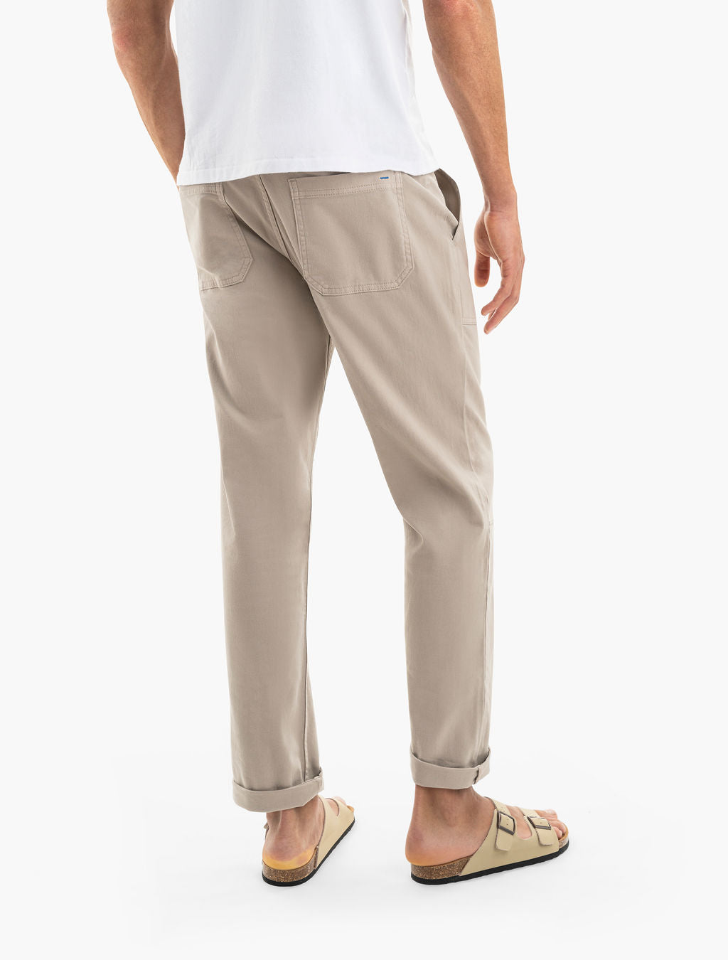 Rear view of a person wearing cuffed beige chinos and tan two-strap sandals