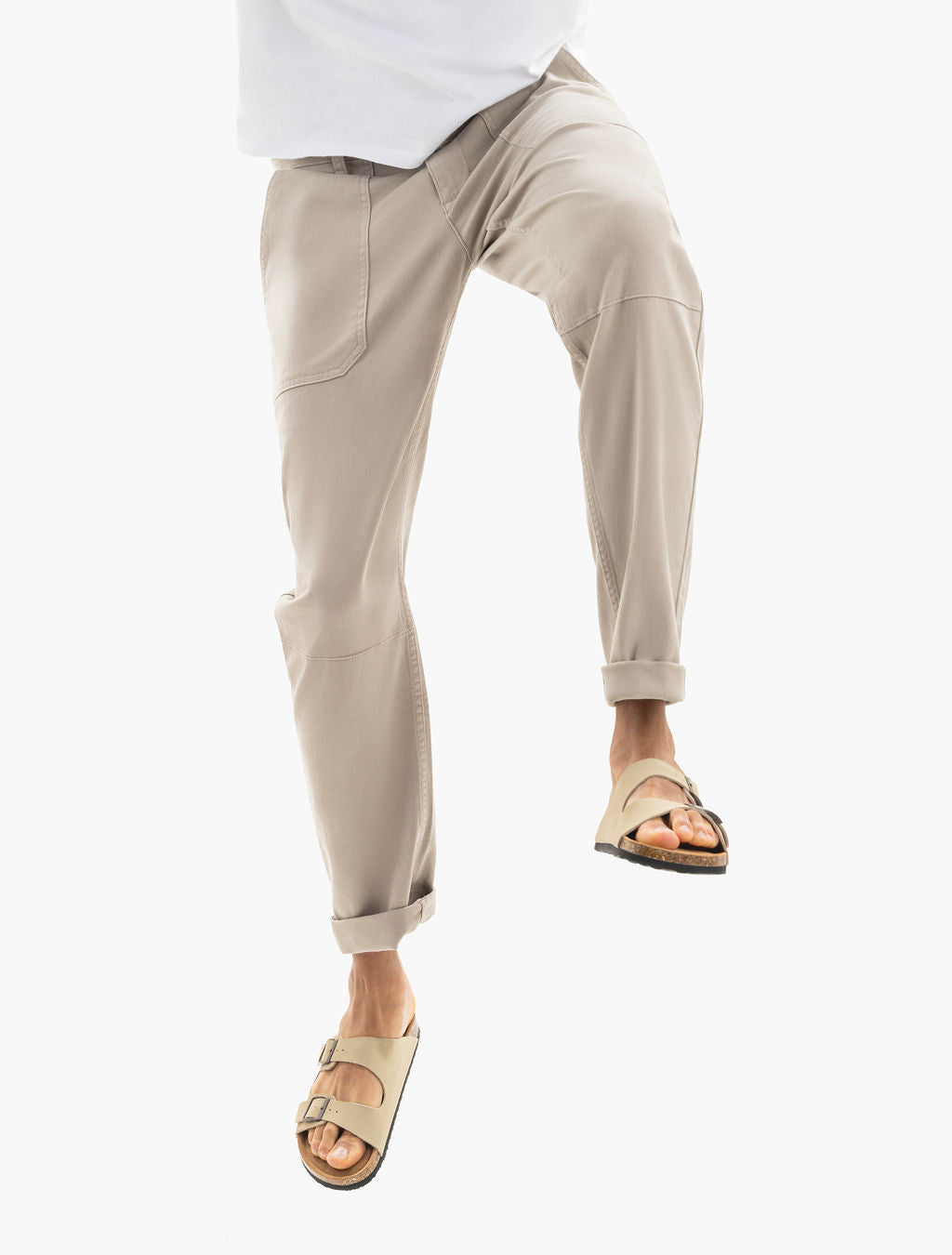 Model wearing rolled-ankle tan utility pants and beige double-strap sandals, shown with one leg lifted