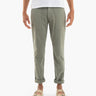 Olive-green tapered pants with front patch pockets and rolled cuffs, shown on a model wearing tan double-strap sandals.