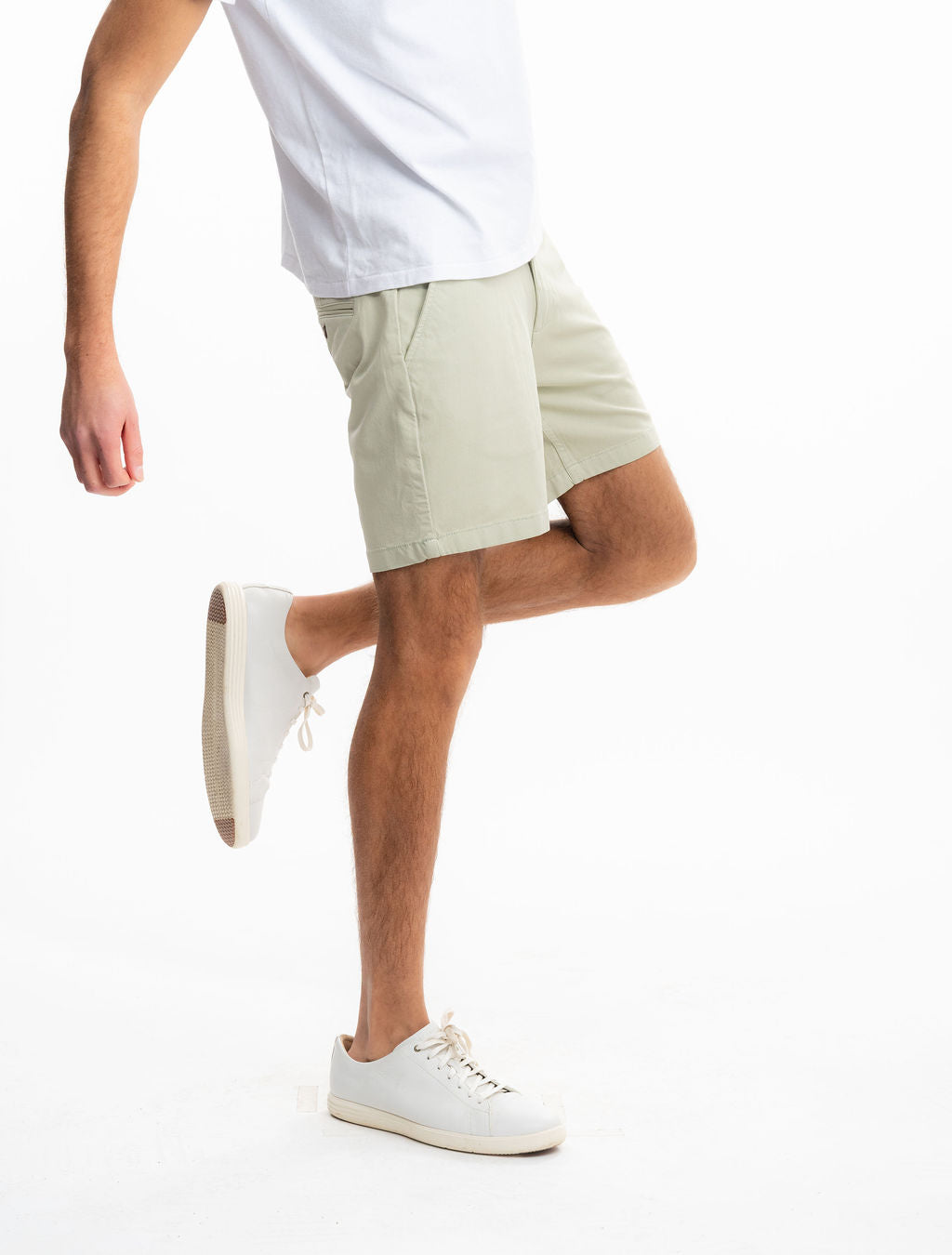 Side view of Willows chino shorts in sage green on model showing mid-thigh length and tailored fit on white background