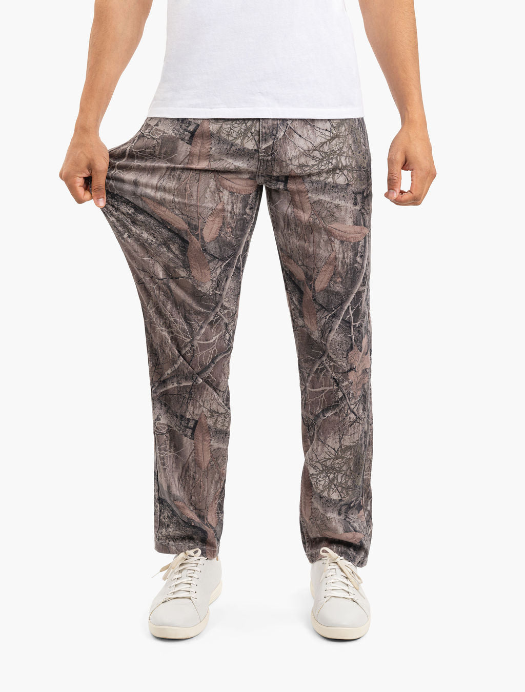 Men's brown Realtree camouflage lounge pants, full-length, model wearing white sneakers, holding fabric to show relaxed fit.