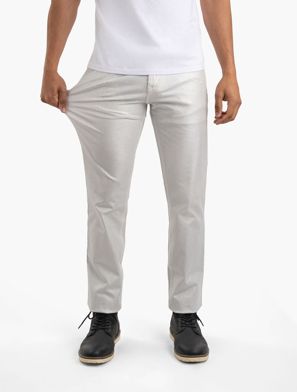 Men’s silver metallic stretch pants, front view; model pulls thigh fabric to show stretch, worn with white tee and black boots