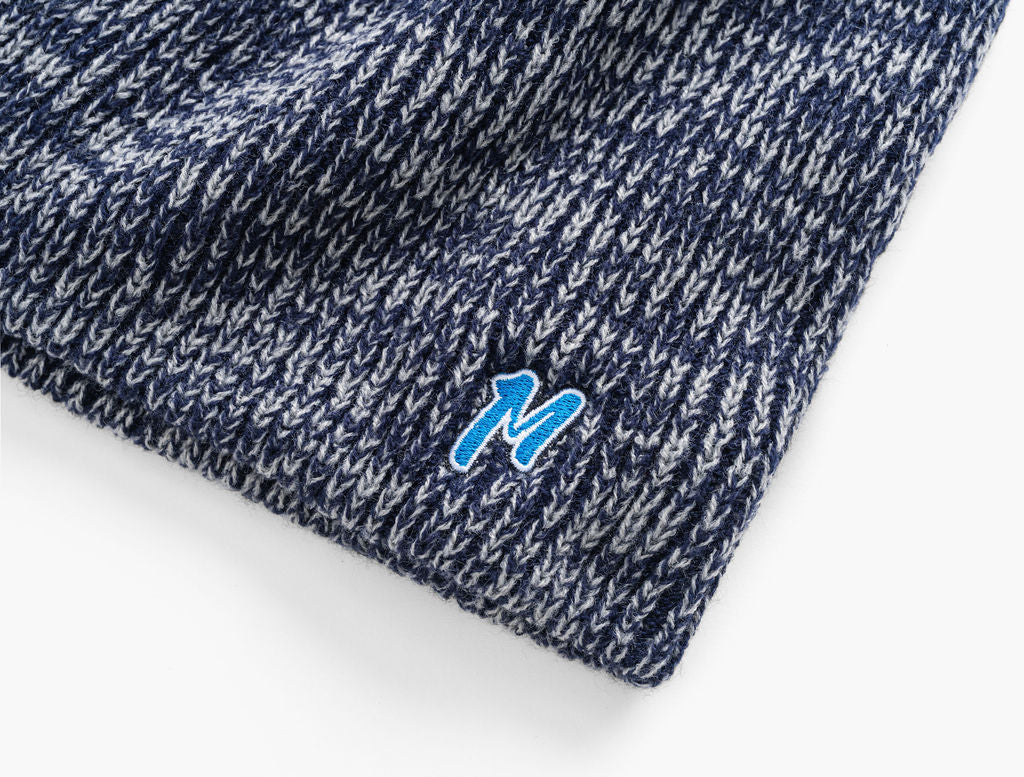 Navy-and-gray marled knit beanie corner with small blue embroidered 'M' logo