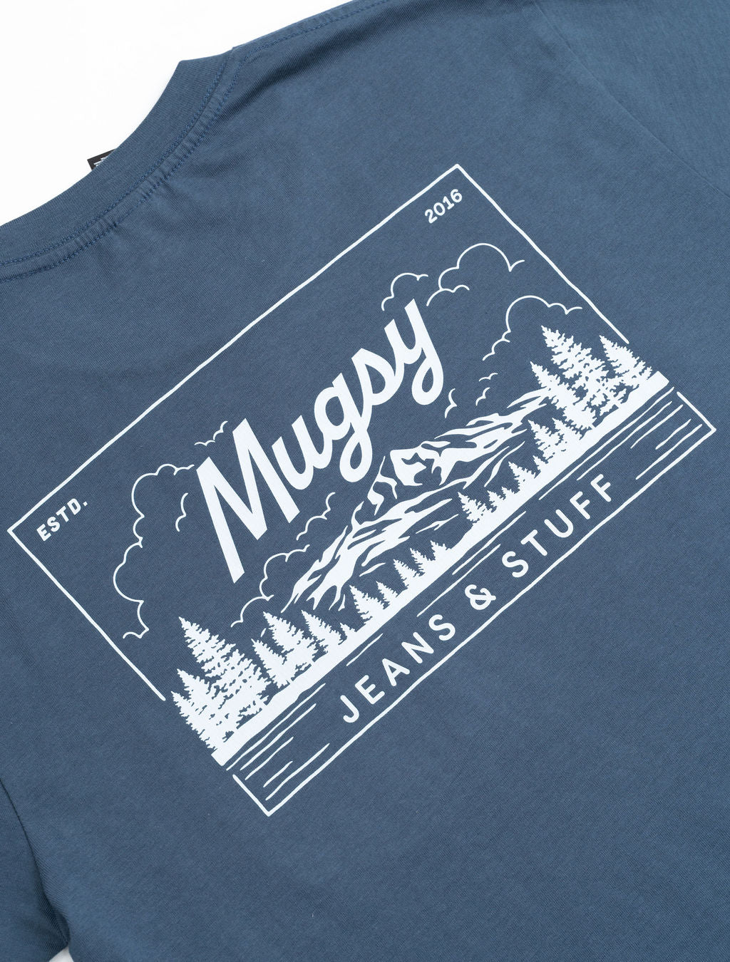 Blue tee back print: Mugsy script over mountain and trees, boxed design reading ESTD. 2016 and JEANS & STUFF