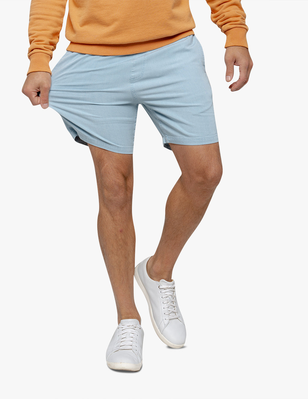 Model wearing light blue shorts with an orange sweatshirt