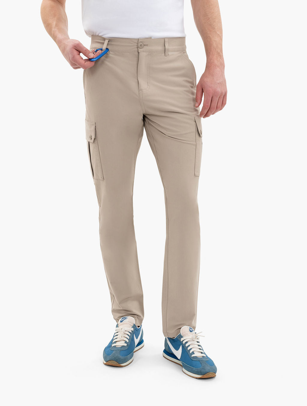 Beige men's cargo pants from waist to shoes, hand placing blue carabiner in front pocket; blue NIKE sneakers.