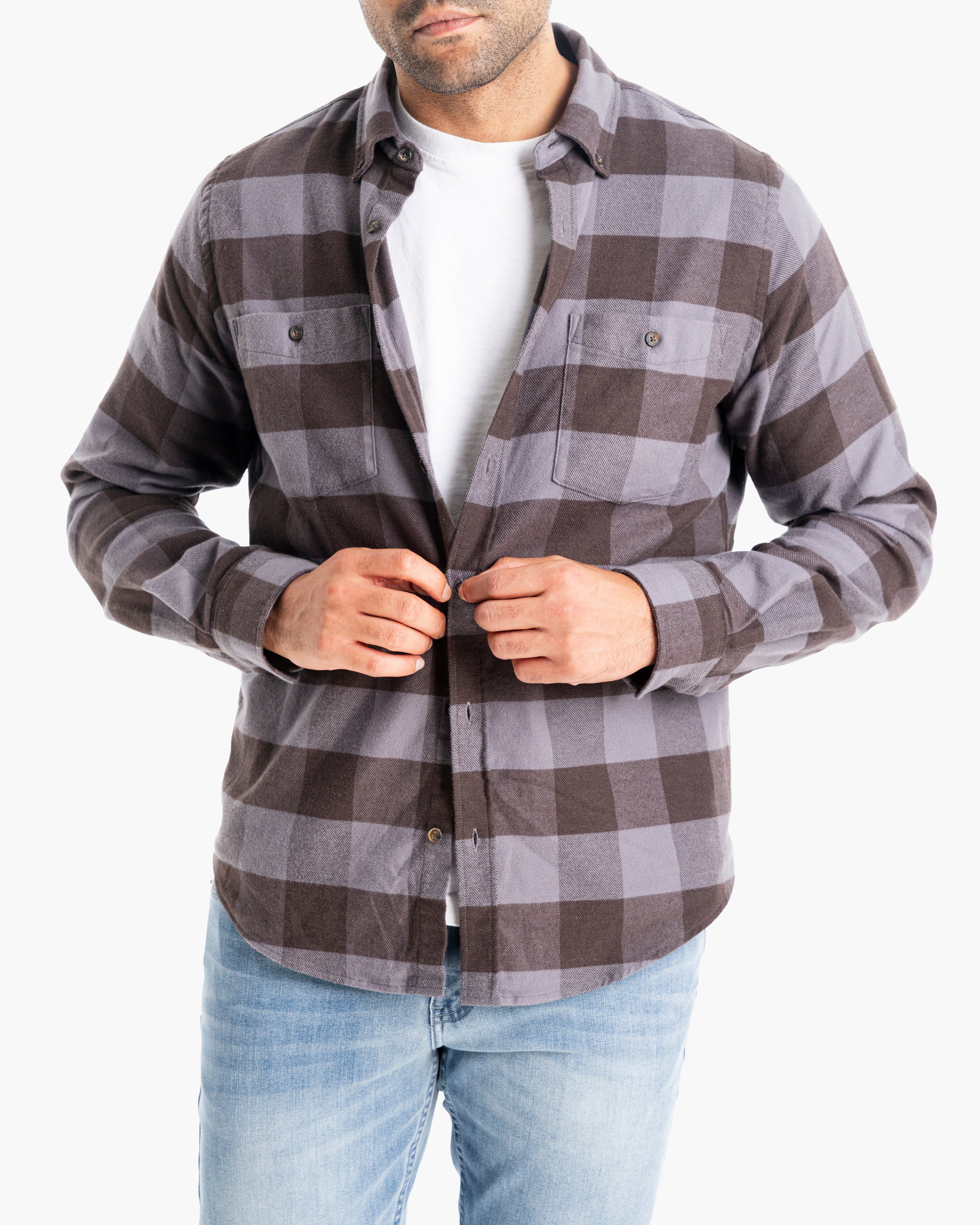 Model wearing a black and gray plaid flannel shirt, buttoned up, with light jeans.