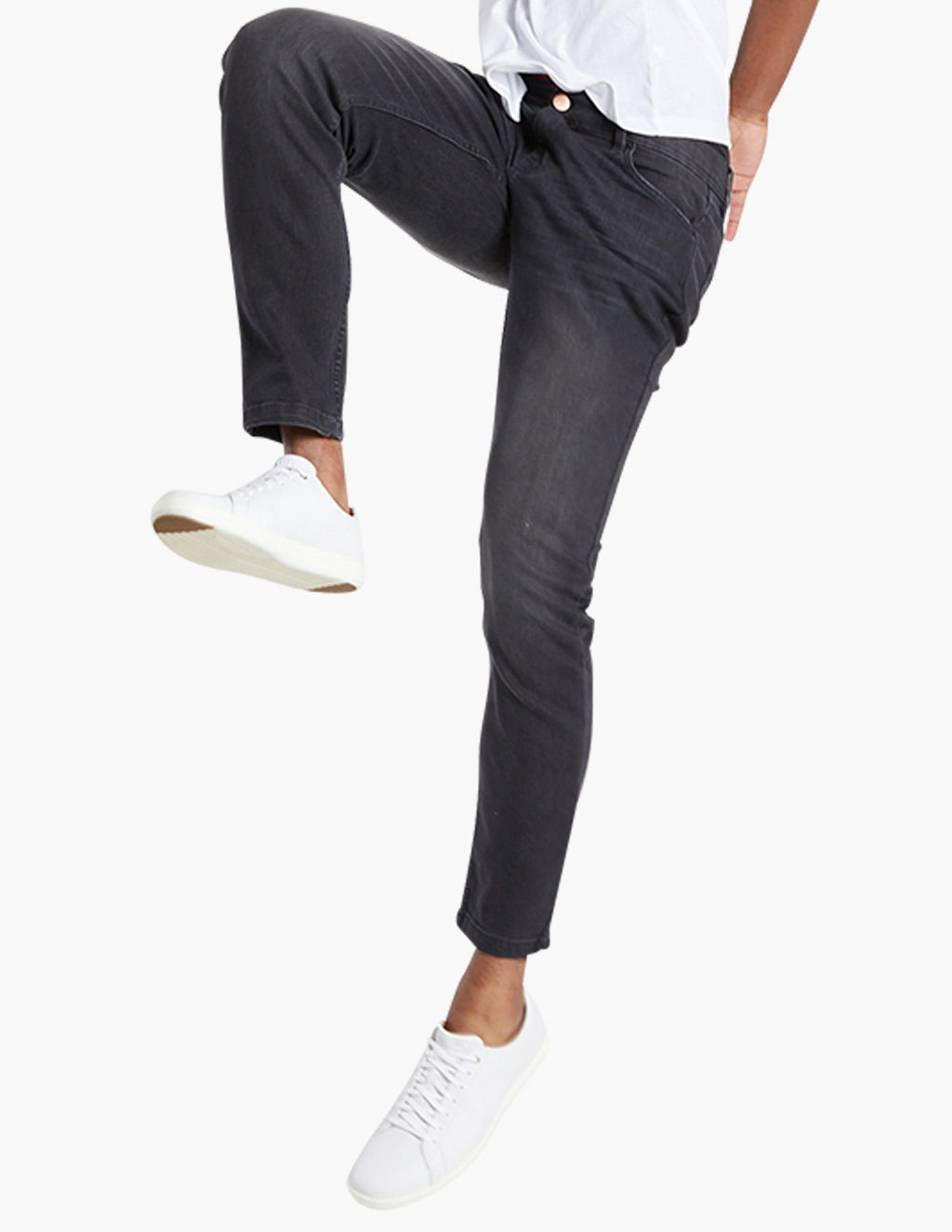 Person wearing black jeans and white sneakers, one leg raised
